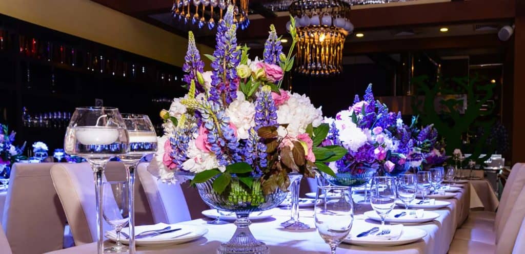 Floral centerpiece of purple, pink and white flowers on a long table. Flowers by Marco Island Flowers.