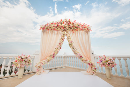 Pink and blush flowers create an elegant outdoor wedding ceremony altar. 