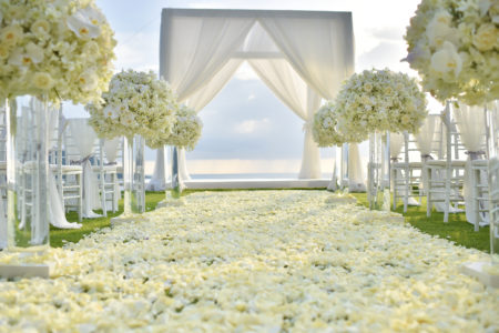 Elegant white flower arrangements and white rose petals leading to a stunning outside wedding ceremony. 