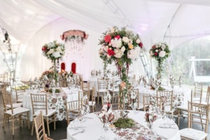 Tall and full flower centerpieces inside a tent for a wedding or event