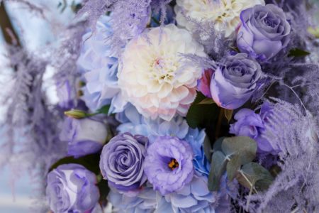 Wedding ceremony decorations: close-up decor of arch, decorated with crysanthemums, roses, hydrangeas and greenery. A lot of flowers in trendy color of the year 2022 - Very Peri.