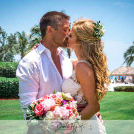 Bride and groom kissing with flowers in the foreground. Wedding bouquet by Marco Island Florist.