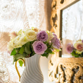 White pitcher vase filled with lavender and pastel yellow flowers sitting in front of a mirror. Flowers by Marco Island Florist.