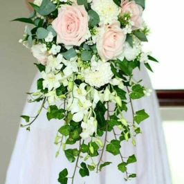 Closeup of cascading bridal bouquet of blush pink roses, white flowers and greenery. Wedding flowers by Marco Island Florist.